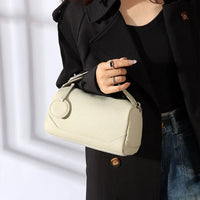 Woman in black coat holding ivory textured leather handbag