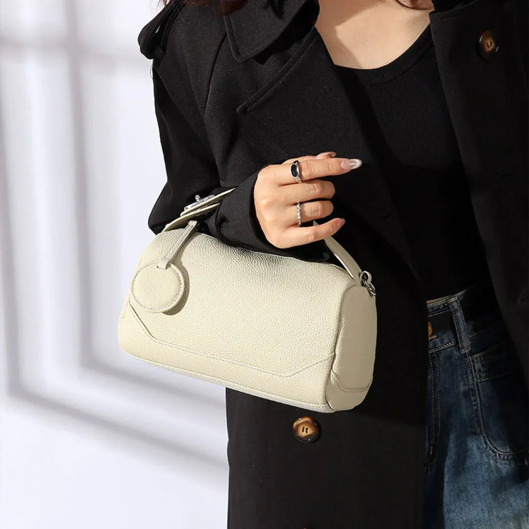 Woman in black coat holding ivory textured leather handbag