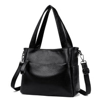 Black leather handbag with double handles and adjustable shoulder strap on white background