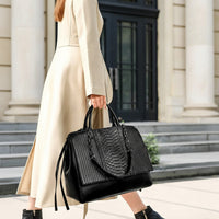 Woman in beige coat carrying black leather tote handbag outside a building with steps
