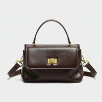 Dark brown leather handbag with gold hardware and top handle, front view on white background