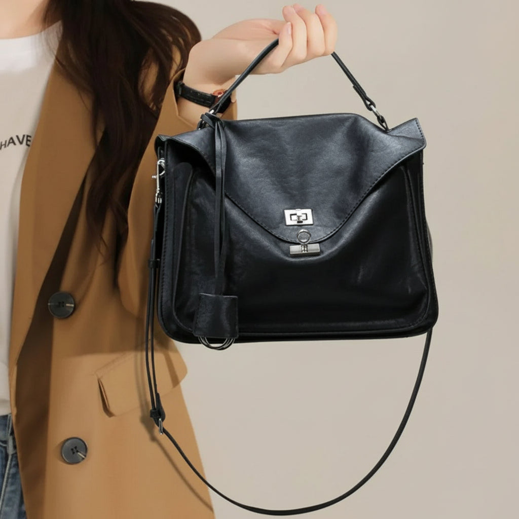 Woman in tan blazer holding stylish black leather handbag with top handle and shoulder strap
