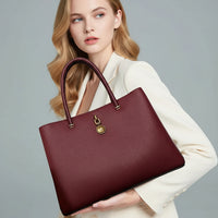 Woman in white blazer holding large burgundy leather tote bag with gold hardware