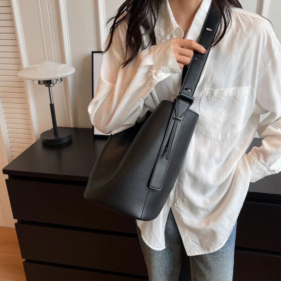 Woman in white shirt with black leather shoulder bag in modern room