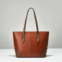 Brown leather tote bag with double handles on a plain white background