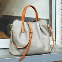 Taupe leather handbag with tan straps on windowsill, stylish women's purse