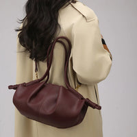 Woman wearing beige trench coat with burgundy leather handbag over shoulder