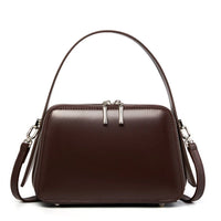 Brown leather handbag with double zipper, top handle, and shoulder strap on white background