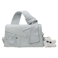 Light blue denim handbag with wide handle and white fuzzy keychain accessory