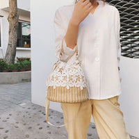 Woman in white blouse holding straw handbag with white floral lace outdoors