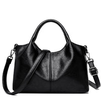 Black leather handbag with top handles and adjustable shoulder strap on white background