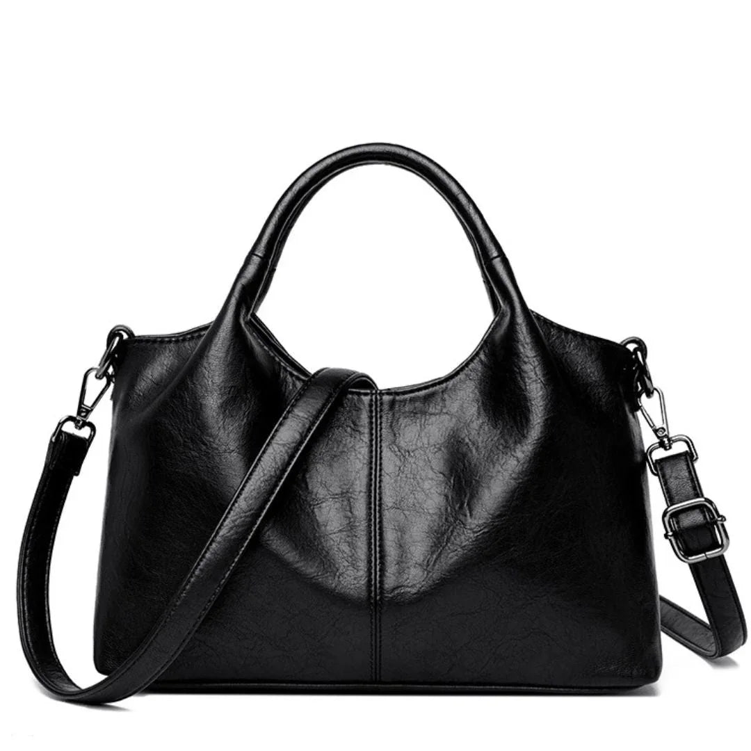 Black leather handbag with top handles and adjustable shoulder strap on white background