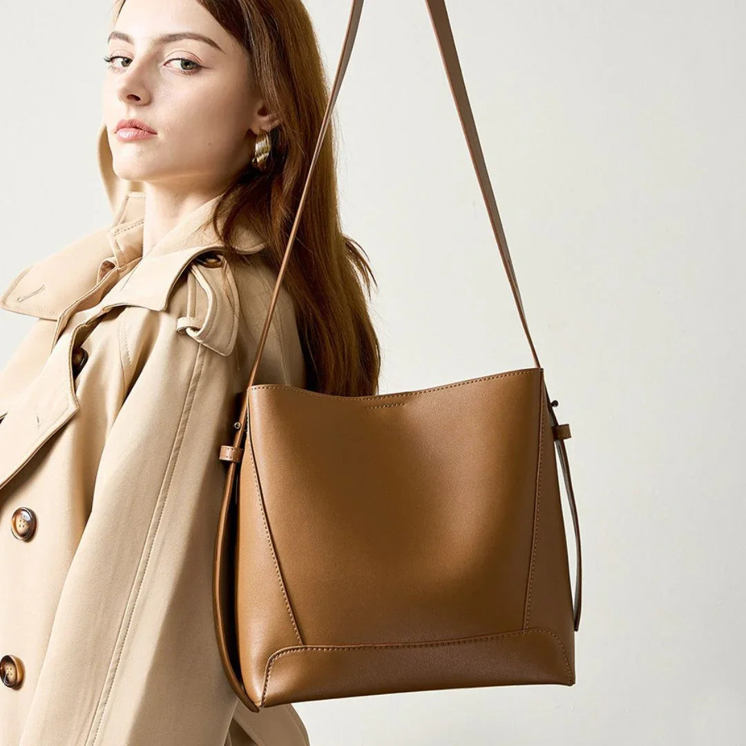 Woman in beige trench coat with brown leather shoulder bag, minimalist fashion style