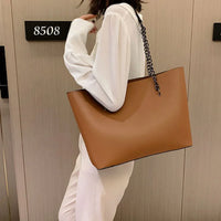 Woman in white outfit holding large brown leather tote bag with chain strap by hotel door 8508