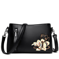 Black leather crossbody bag with floral embroidery and zippered pocket