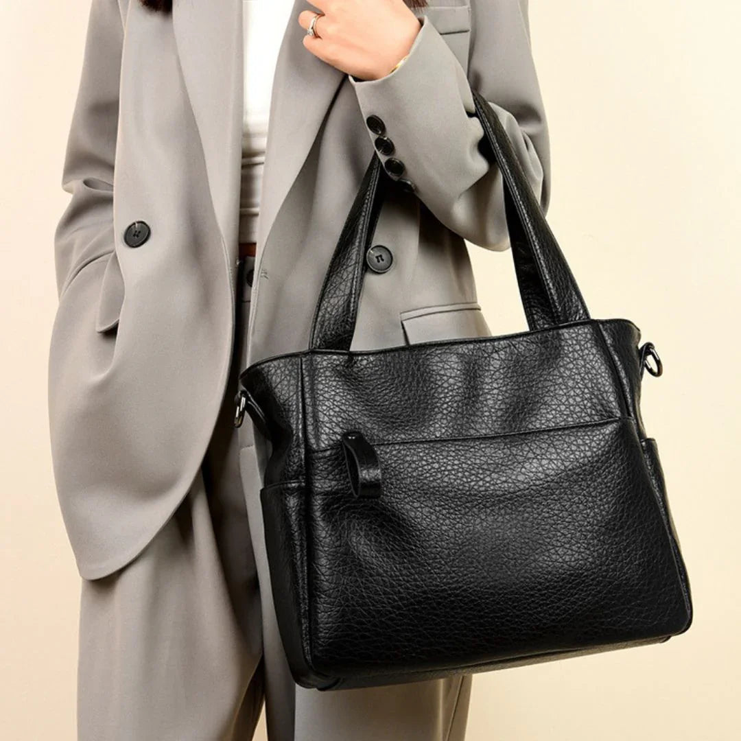 Woman in gray suit holding textured black leather tote bag