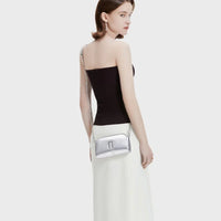Woman in black tube top and white skirt with metallic silver crossbody bag