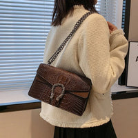 Woman wearing cream textured jacket with a brown crocodile pattern shoulder bag indoors
