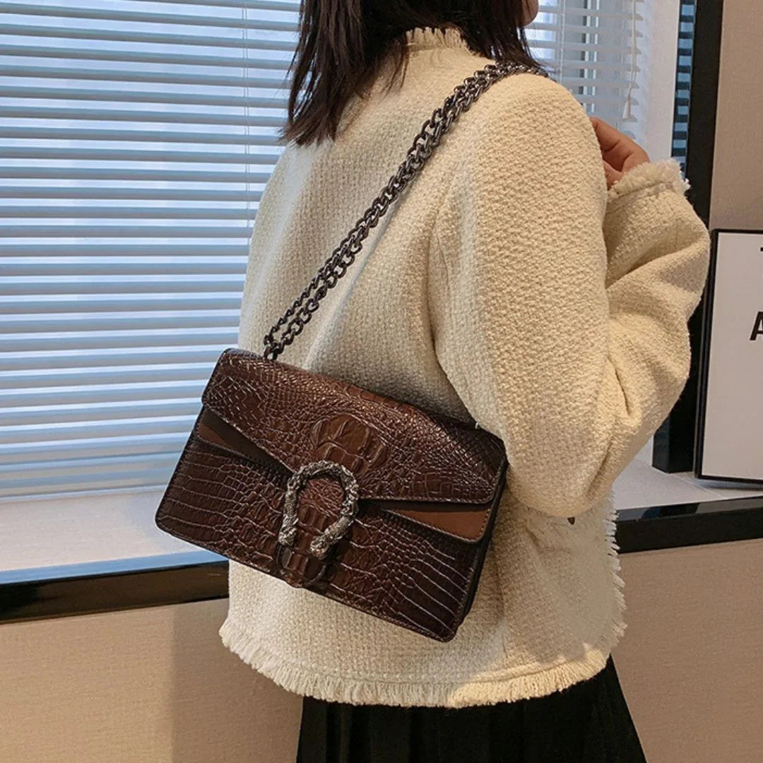 Woman wearing cream textured jacket with a brown crocodile pattern shoulder bag indoors
