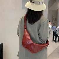 Woman in beige hat and blazer with shiny red shoulder bag in modern cafe