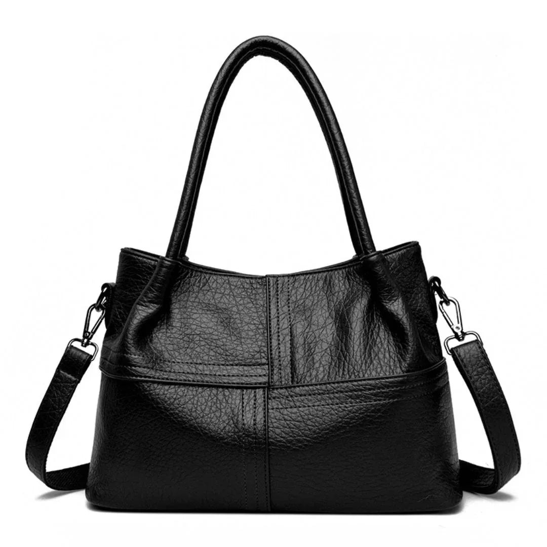 Black leather handbag with shoulder strap and top handles on white background