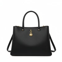 Black leather handbag with gold medallion pendant and shoulder strap on white background