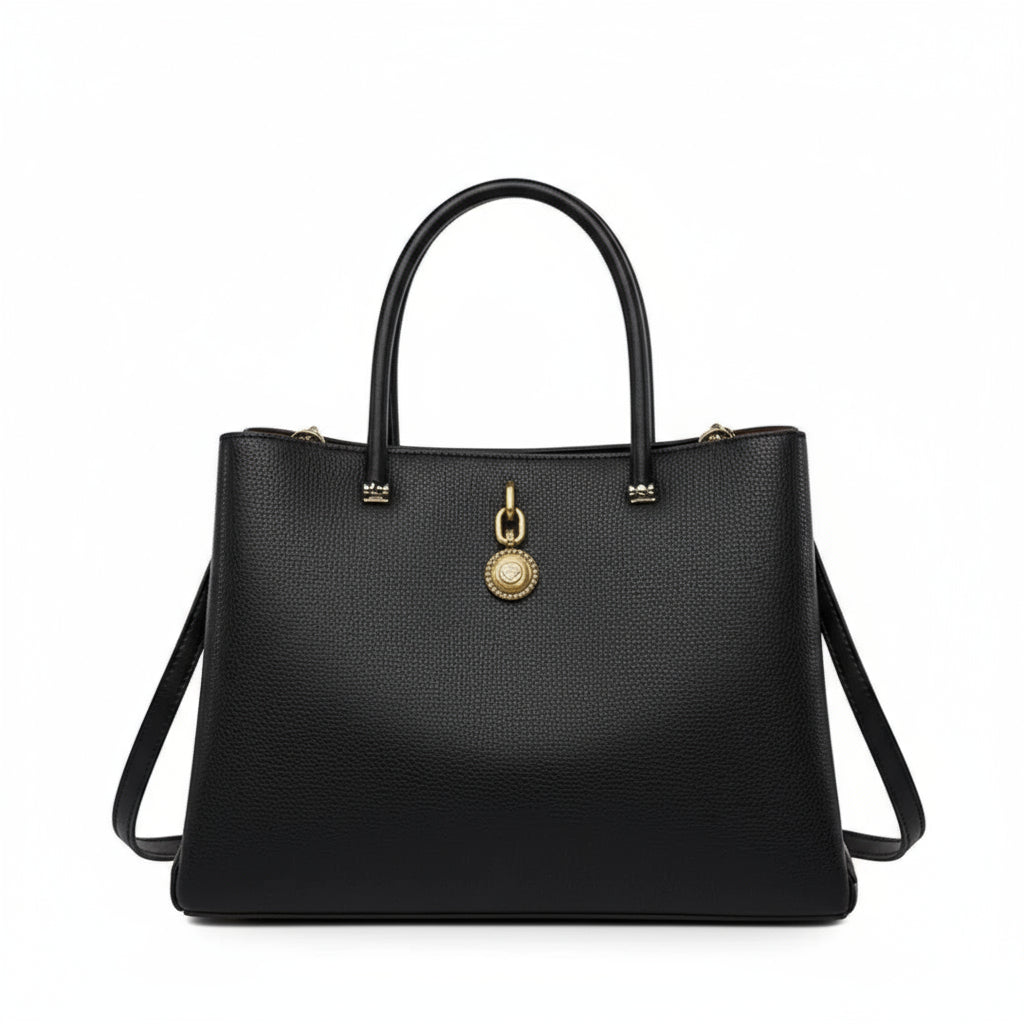 Black leather handbag with gold medallion pendant and shoulder strap on white background