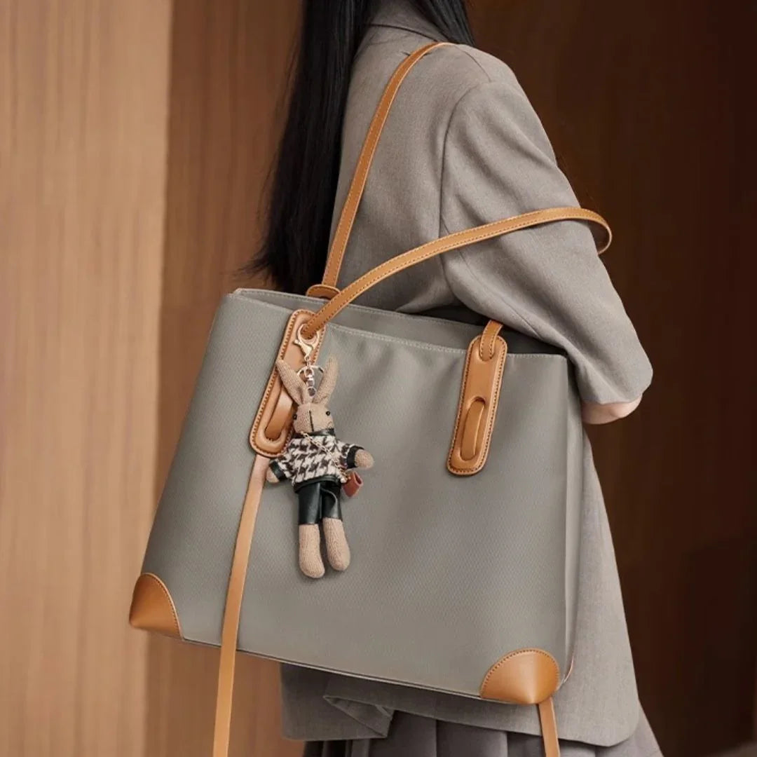 Woman with large gray tote bag featuring tan leather accents and bunny keychain