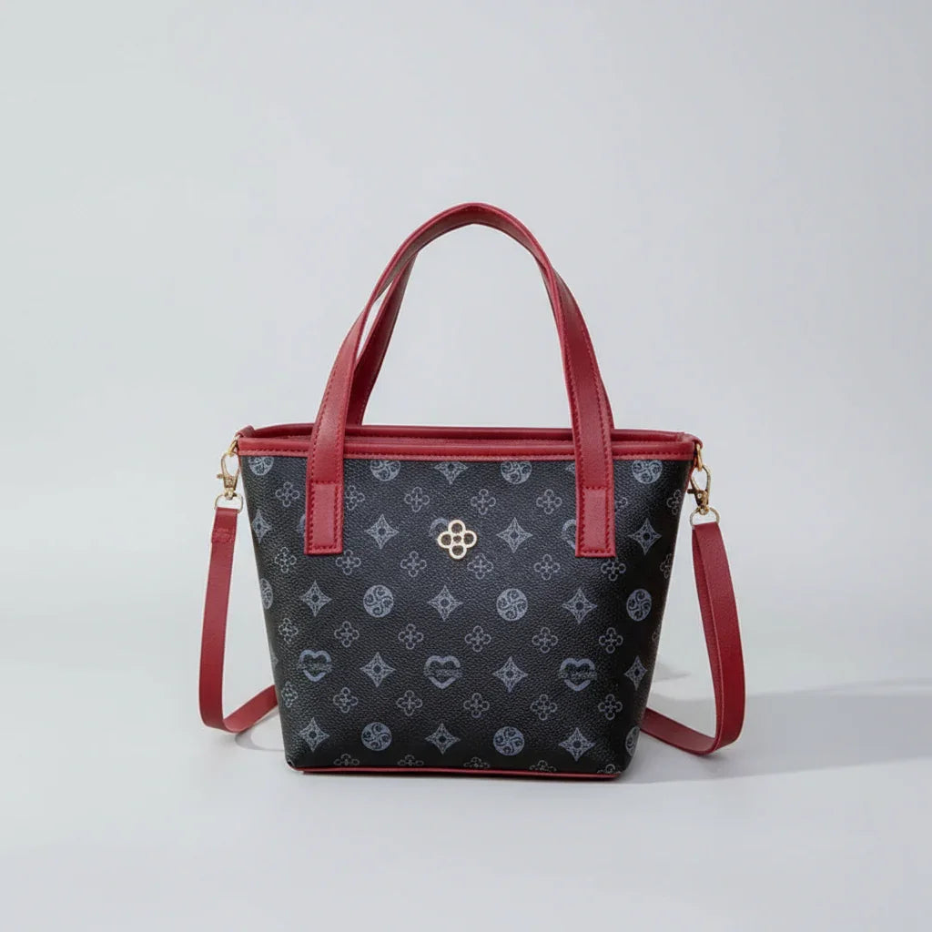 Black handbag with red handles, floral pattern, gold logo, and detachable shoulder strap