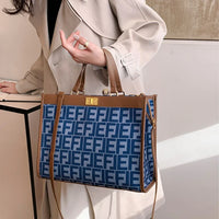 Woman in beige trench coat holding blue patterned tote bag with brown leather trim