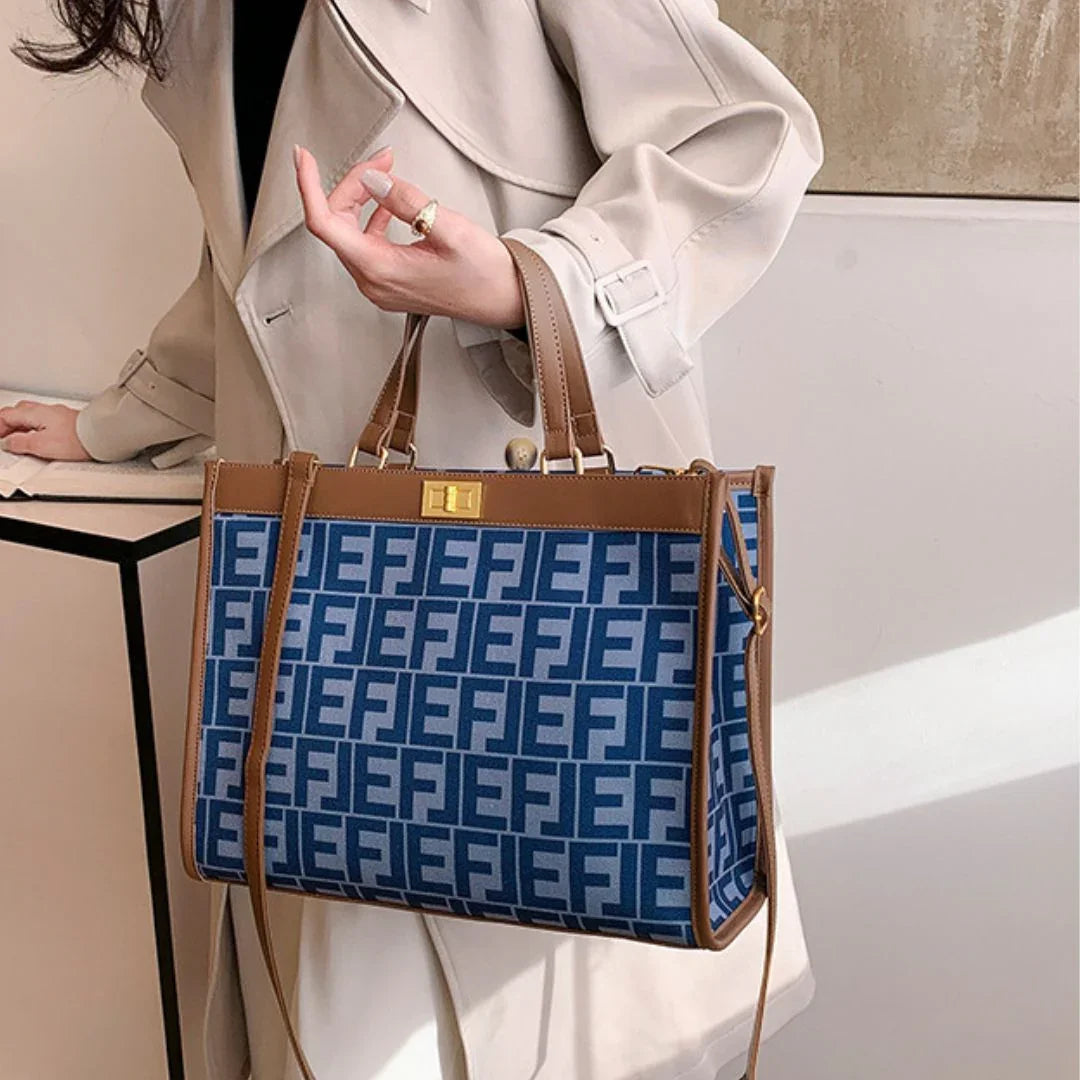 Woman in beige trench coat holding blue patterned tote bag with brown leather trim