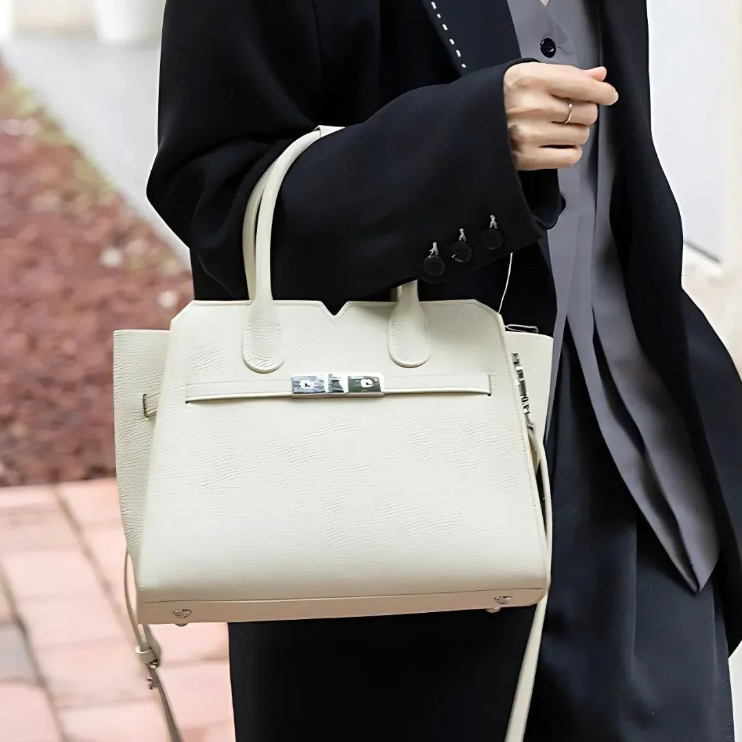 Woman wearing black blazer holding stylish white leather handbag outdoors