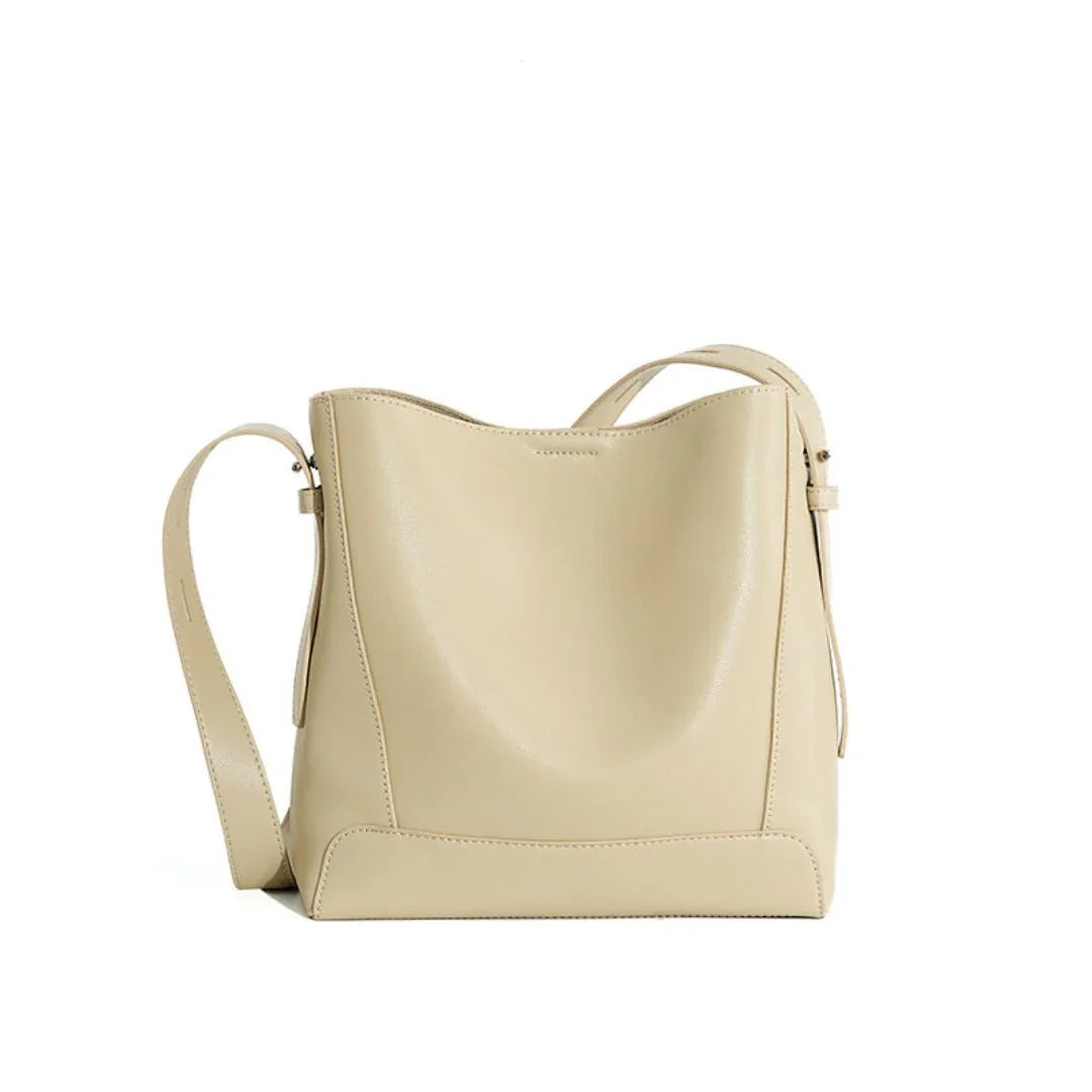 Beige leather bucket bag with adjustable strap on white background