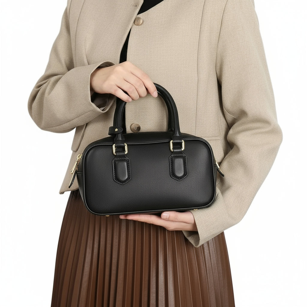 Woman in beige blazer holding black leather handbag with gold hardware