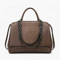 Brown leather handbag with snakeskin pattern, metal chain straps, and top handle on white background