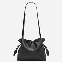 Black leather crossbody bag with drawstring sides and adjustable strap on white background