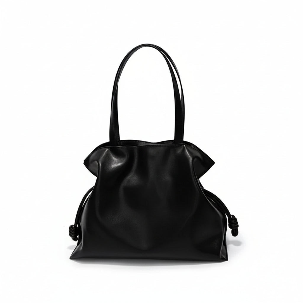 Black leather tote bag with knotted side details and double handles on white background