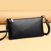 Black leather crossbody purse with geometric stitching on a beige background