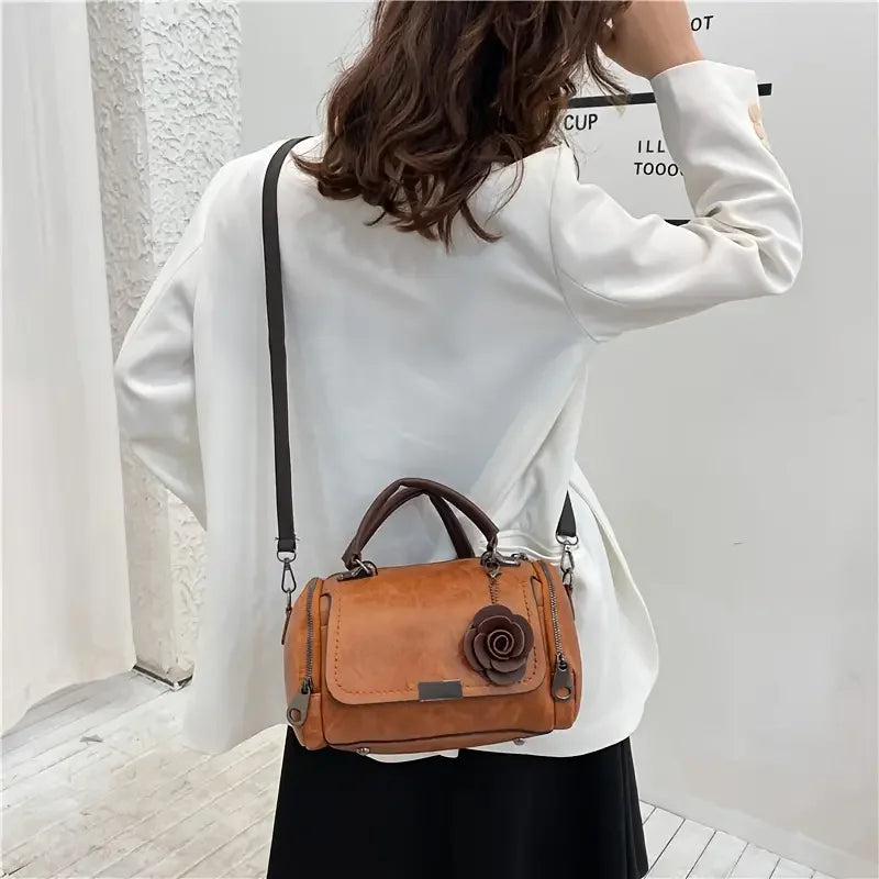 Woman in white blazer with brown leather handbag featuring a flower design