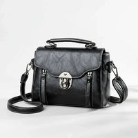 Black leather crossbody satchel bag with silver buckle and top handle on white background