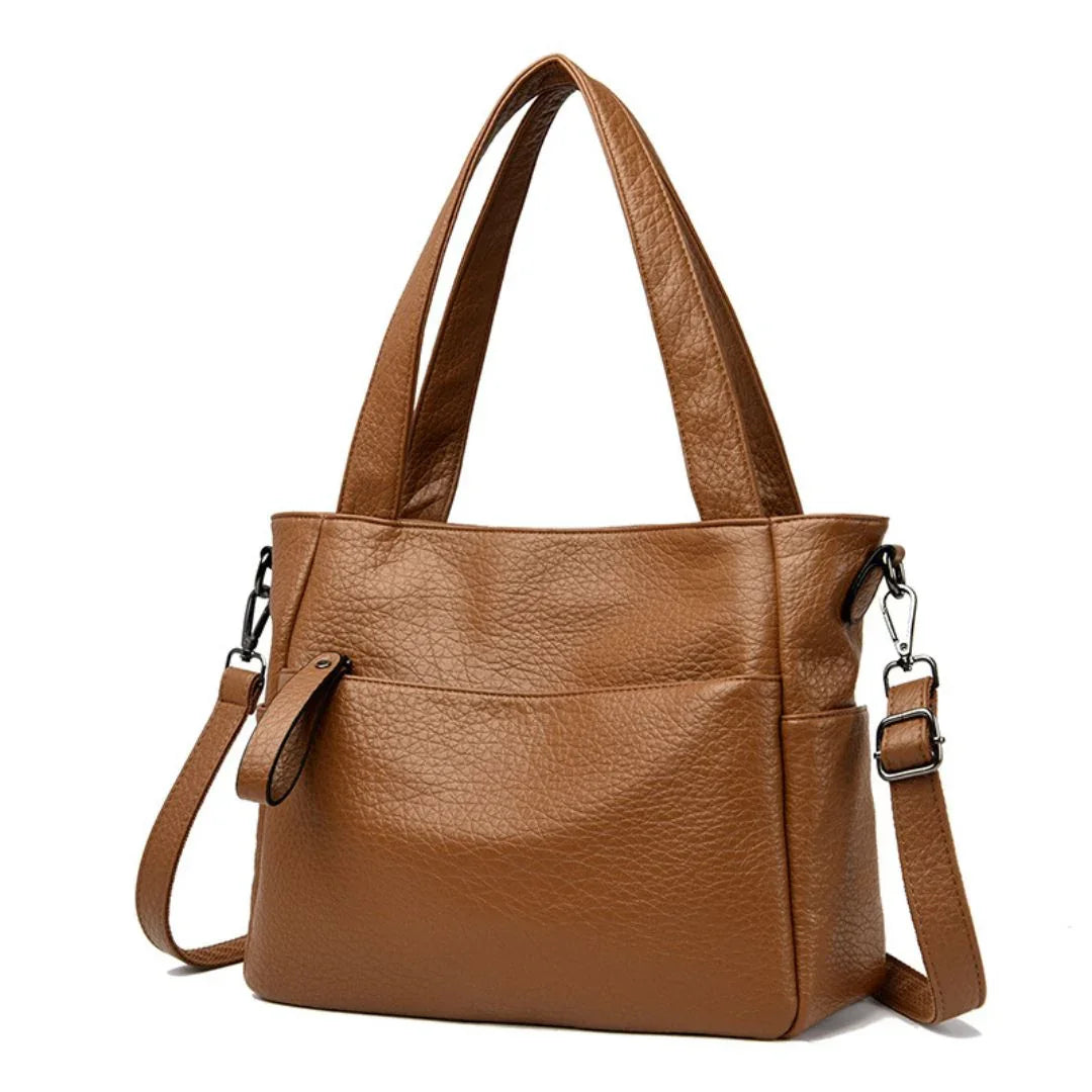 Brown leather tote bag with double handles and detachable shoulder strap on white background