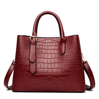 Burgundy crocodile-embossed leather handbag with top handles and shoulder strap