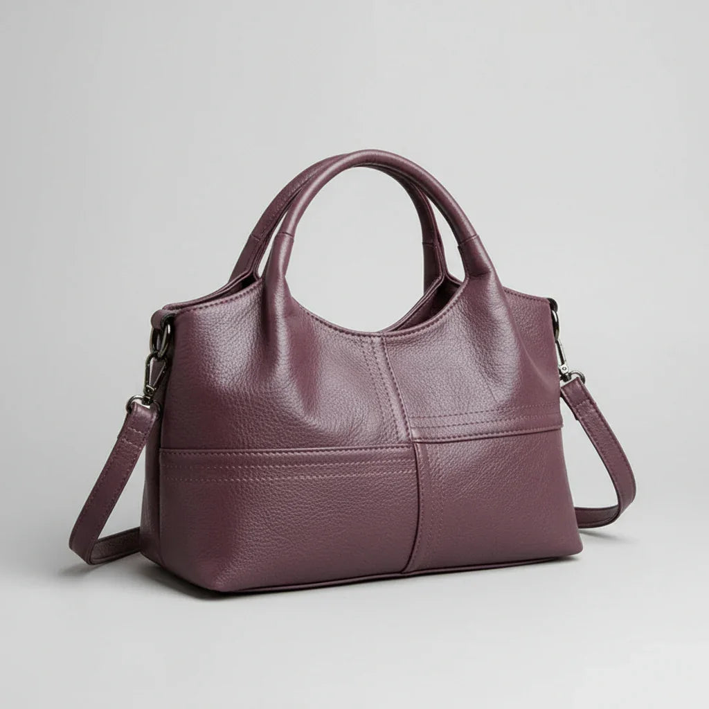 Plum purple leather handbag with top handles and detachable shoulder strap on white background