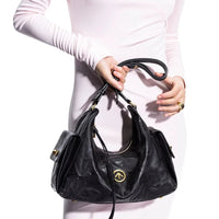 Woman in white dress holding a black leather designer handbag with gold accents