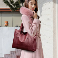 Woman in pink fur collar coat carrying a large burgundy leather tote bag outdoors