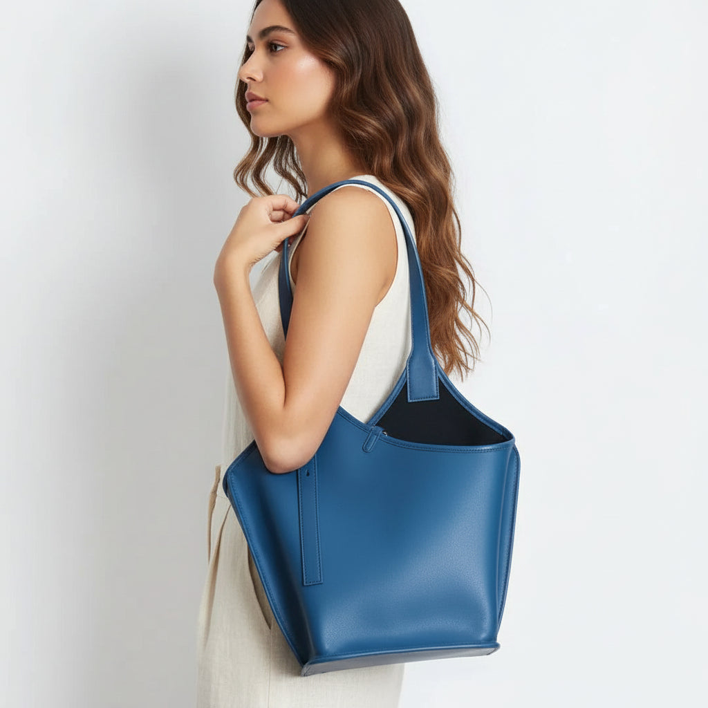 Woman in white dress carrying a large blue leather tote bag on her shoulder
