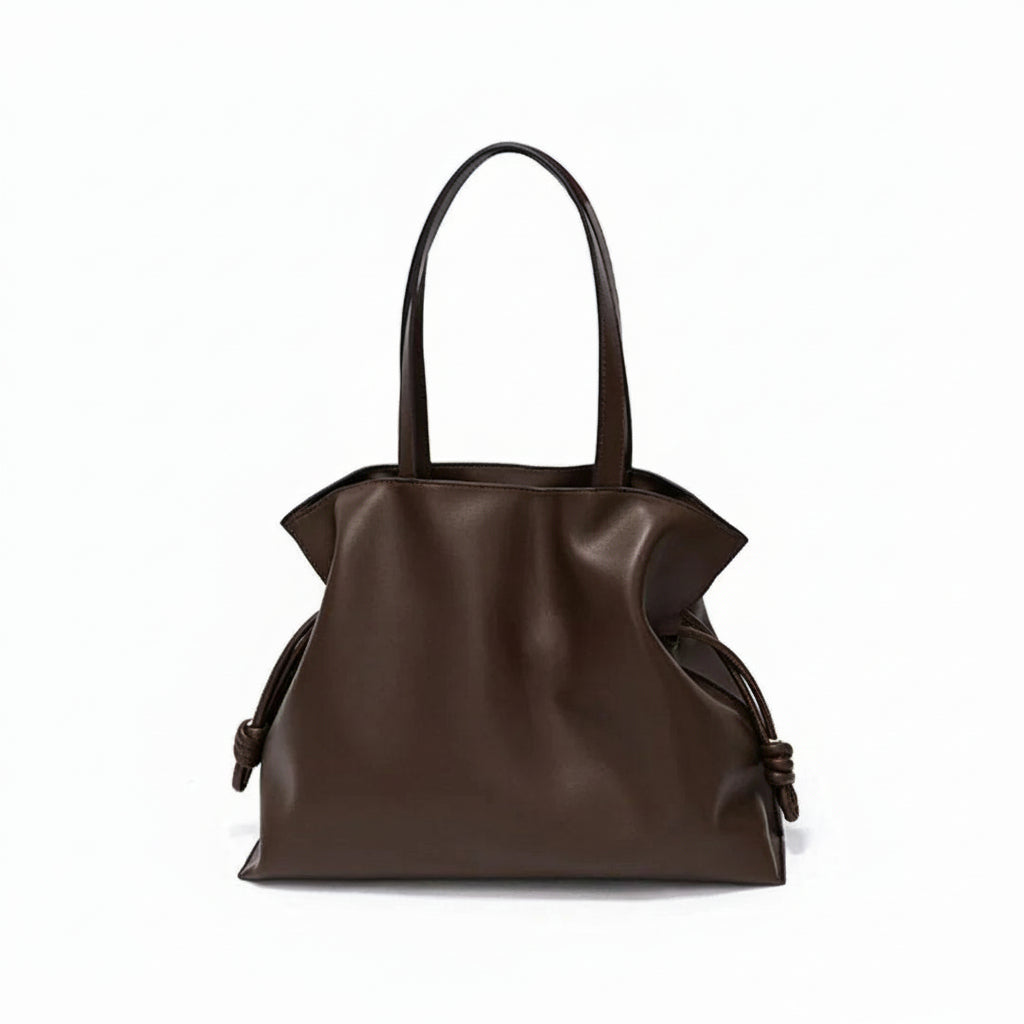 Brown leather tote bag with knotted side details on a white background