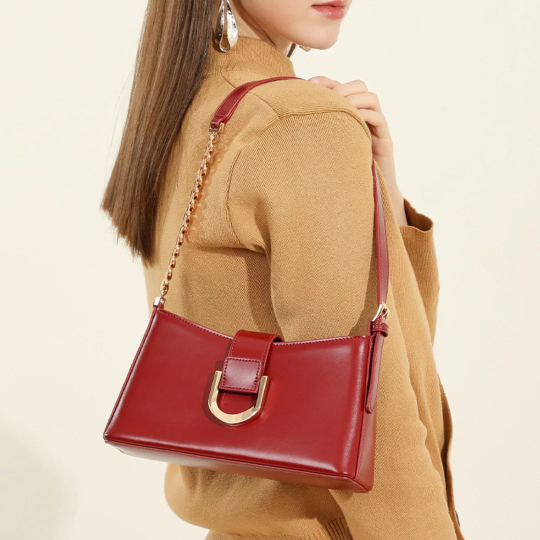 Woman wearing a camel coat and carrying a red leather shoulder bag with gold chain strap