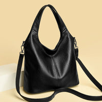 Black leather tote bag with detachable strap on beige background