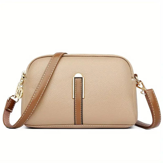 Beige leather crossbody bag with gold clasps and brown adjustable strap on white background